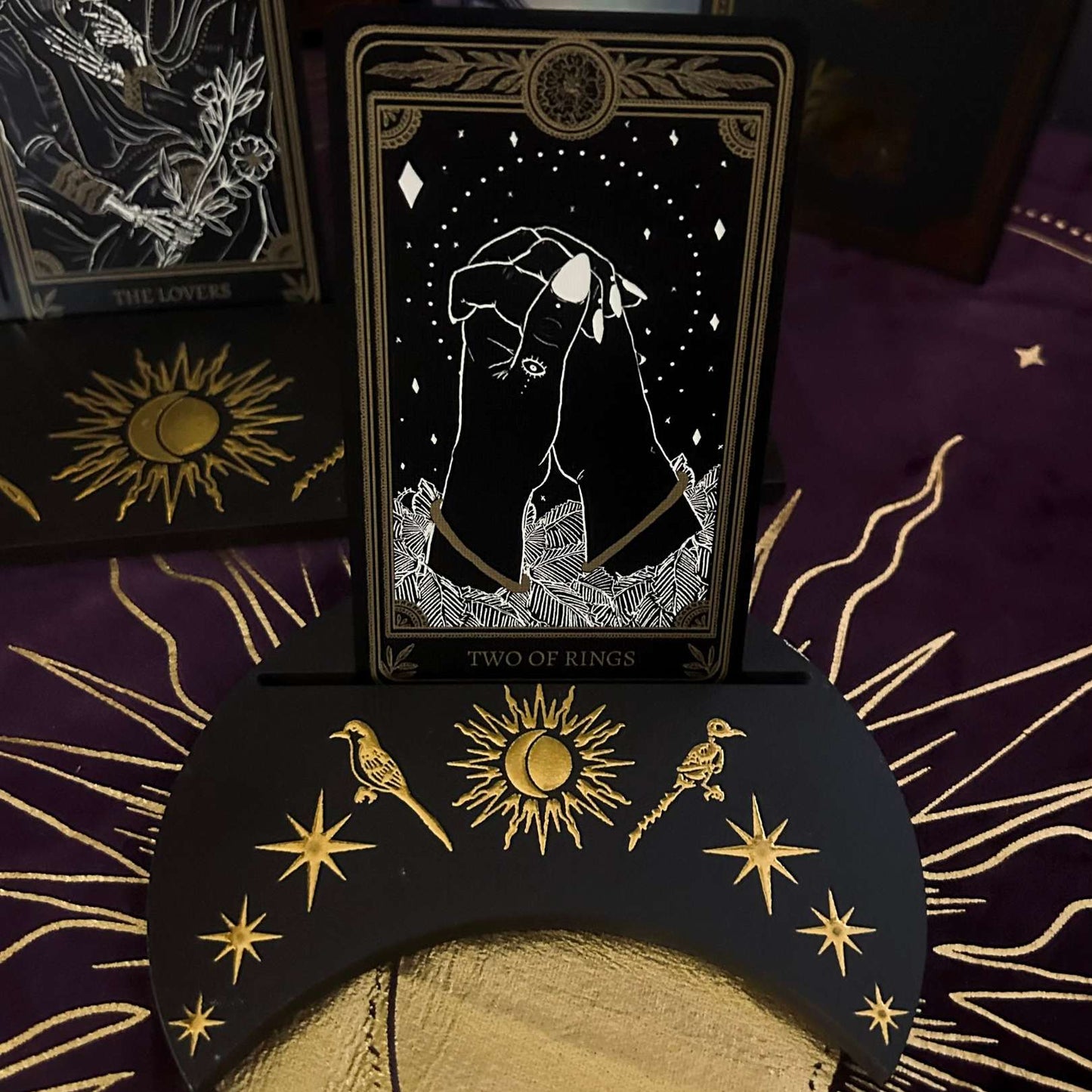 Tarot card featuring a hand holding a moon with decorative cards and symbols in the background.