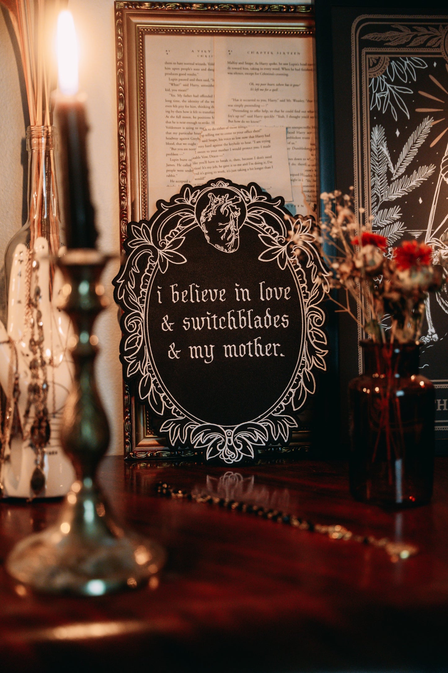 black and white iron-on embroidered back patch design from the Marigold Tarot deck by Amrit Brar and 13th Press. Text reads "i believe in love, switchblades, and my mother"