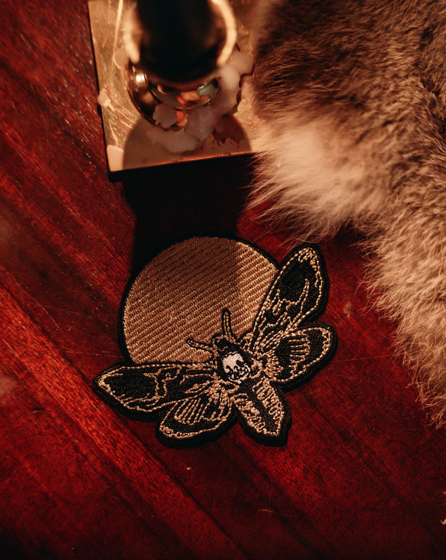 embroidered iron-on patch of moth and moon design by Amrit Brar and 13th Press. Machine embroidered with black, white, and gold thread.