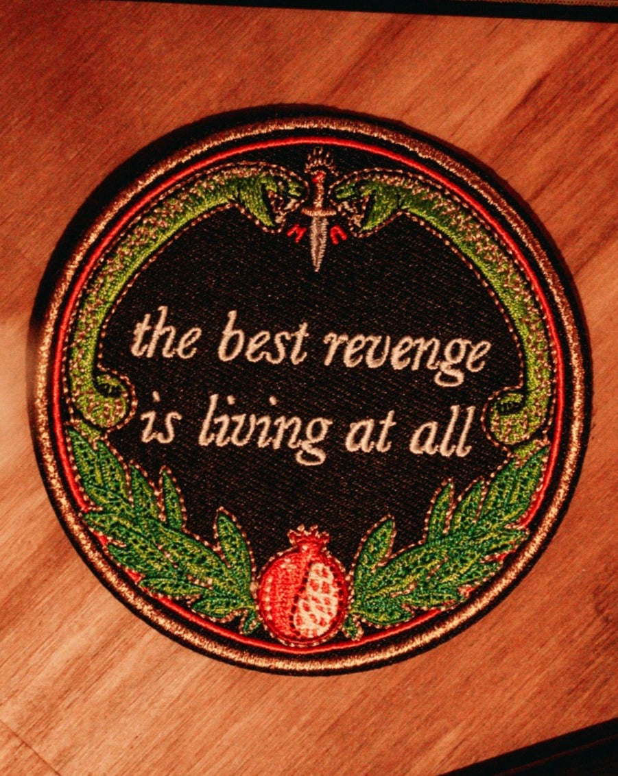 machine embroidered iron-on patch designed by Amrit Brar and 13th Press reads "the best revenge is living at all" with two serpents and pomegranate with leaves