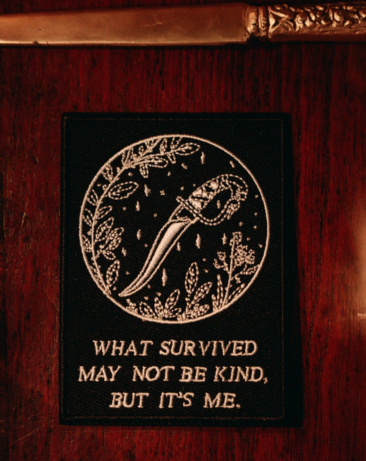 black and white embroidered iron-on patch with dagger and foliage designed by Amrit Brar and 13th Press. Iron-on backing and machine embroidered design.