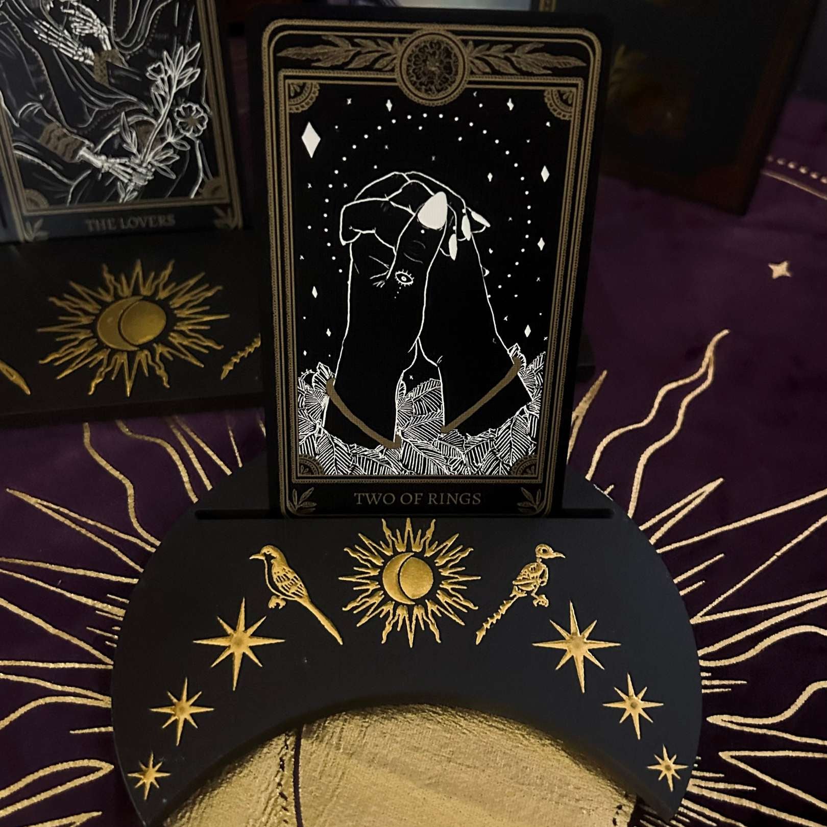 Tarot card featuring a hand holding a moon with decorative cards and symbols in the background.