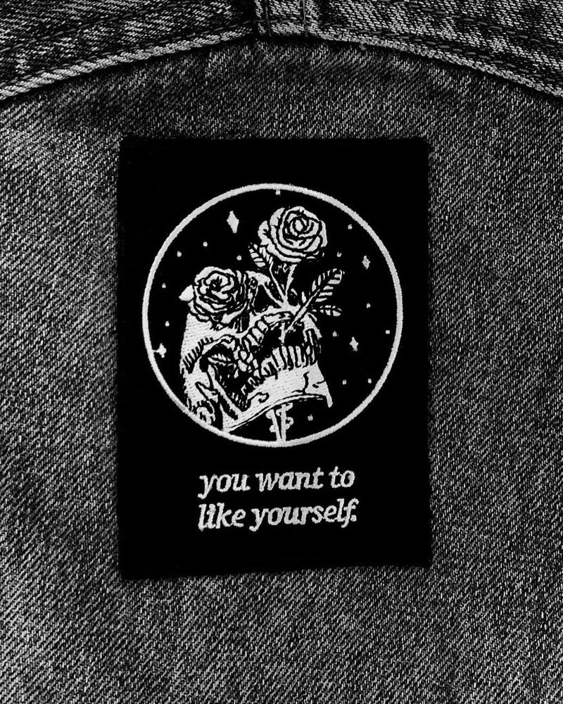 black and white embroidered iron-on patch with skull and rose design by Amrit Brar and 13th Press. Text reads "you want to like yourself".