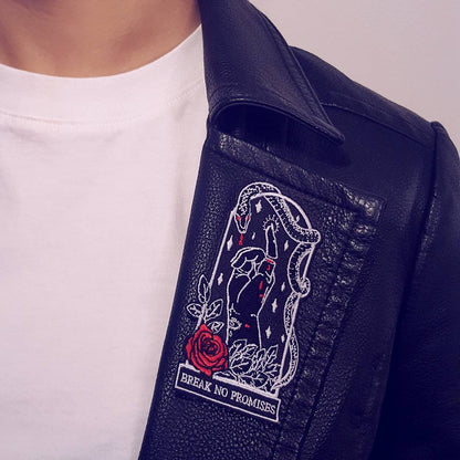 2.5"Wx4"H coffin-shaped embroidered patch featuring an iron-on backing. Patch reads "break no promises." We recommend that you apply a few stitches so the corners do not lift. Designed by Amrit Brar, produced by 13th Press. Embroidered patch, iron-on patch, denim patch, leather patch, biker patch, punk patch