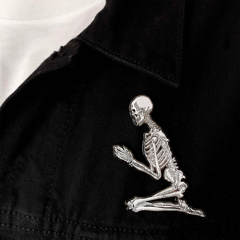 metal hard enamel pin set of two skeletons in prayer position designed by Amrit Brar and 13th Press on denim jacket