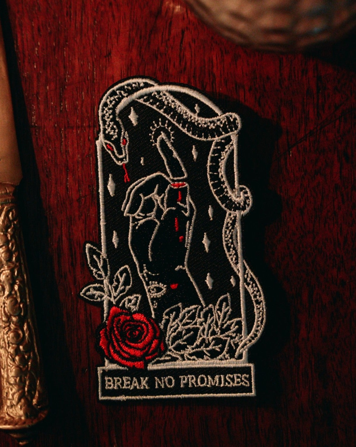 black, white, and red thread embroidered patch of rose, foliage, serpent, and pinky promise designed by Amrit Brar and 13th Press