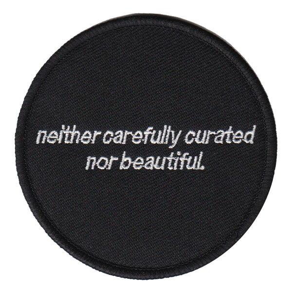 black and white machine embroidered iron-on patch that reads "neither carefully curated nor beautiful" designed by Amrit Brar and 13th Press