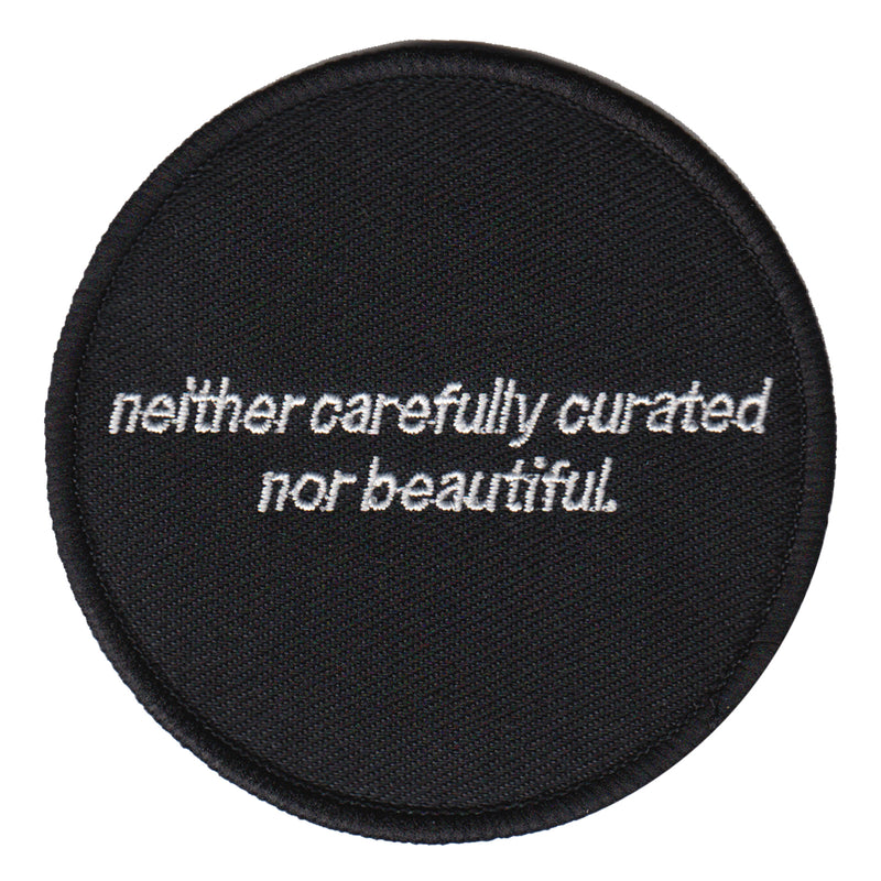 black and white machine embroidered iron-on patch that reads "neither carefully curated nor beautiful" designed by Amrit Brar and 13th Press