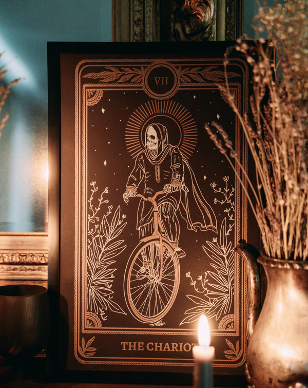 art print of the chariot tarot card from the Marigold Tarot deck by Amrit Brar and 13th Press. print of skeleton on chariot on altar with candle light and dried flowers