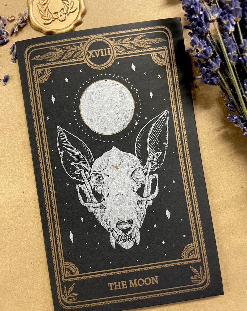 Greeting card featuring the "Moon" tarot card design from the Marigold Tarot deck.  - Dimensions:  - Metallic printed  - Blank, white inside  - 250gsm paper  - Includes 100gsm black envelope  - Includes gold logo wax seal