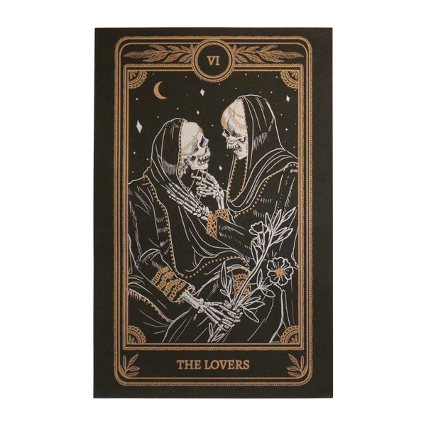 art print of the Lovers card from the Marigold Tarot deck by Amrit Brar and 13th Press on altar stand with lit candles and tarot card spread. Art of two skeletons embracing with flowers.