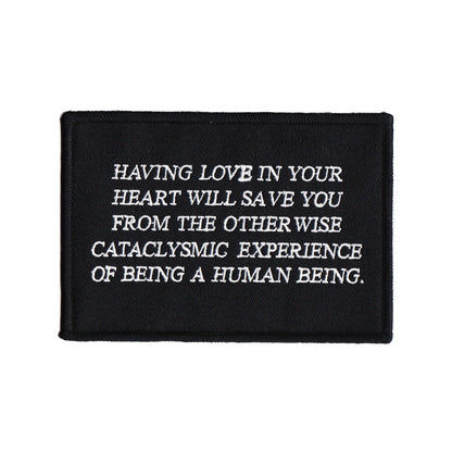 black and white embroidered iron-on patch designed by Amrit Brar and 13th Press. Text reads "having love in your heart will save you from the otherwise cataclysmic experience of being a human being"
