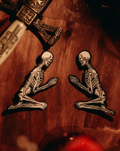 metal hard enamel pin set of two skeletons in prayer position designed by Amrit Brar and 13th Press