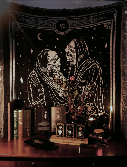 woven tapestry of the Lovers tarot card from the Marigold Tarot deck by Amrit brar and 13th Press. Hung above altar area with tarot deck, wooden tarot card stand, books, and candles.