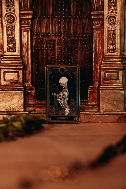 hard enamel pin of strength tarot card from the Marigold Tarot deck by Amrit Brar and 13th Press. Black pin with gold and white ink. Pin for jackets and bags