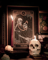 Tarot Devil print from the Marigold Tarot deck by Amrit Brar and 13th Press. With skull and candle decor on altar. Skeleton and serpent. Gold ink