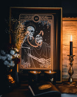 Tarot Devil print from the Marigold Tarot deck by Amrit Brar and 13th Press. With skull and candle decor on altar. Skeleton and serpent. Gold ink
