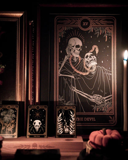 Tarot Devil print from the Marigold Tarot deck by Amrit Brar and 13th Press. With skull and candle decor on altar. Skeleton and serpent. Gold ink