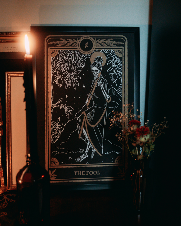 tarot print of the Fool card from the Marigold Tarot deck by Amrit Brar and 13th Press on altar stand with candle and roses.