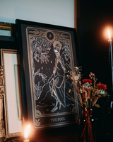 tarot print of the Fool card from the Marigold Tarot deck by Amrit Brar and 13th Press in gold frame on altar stand with candle and roses.