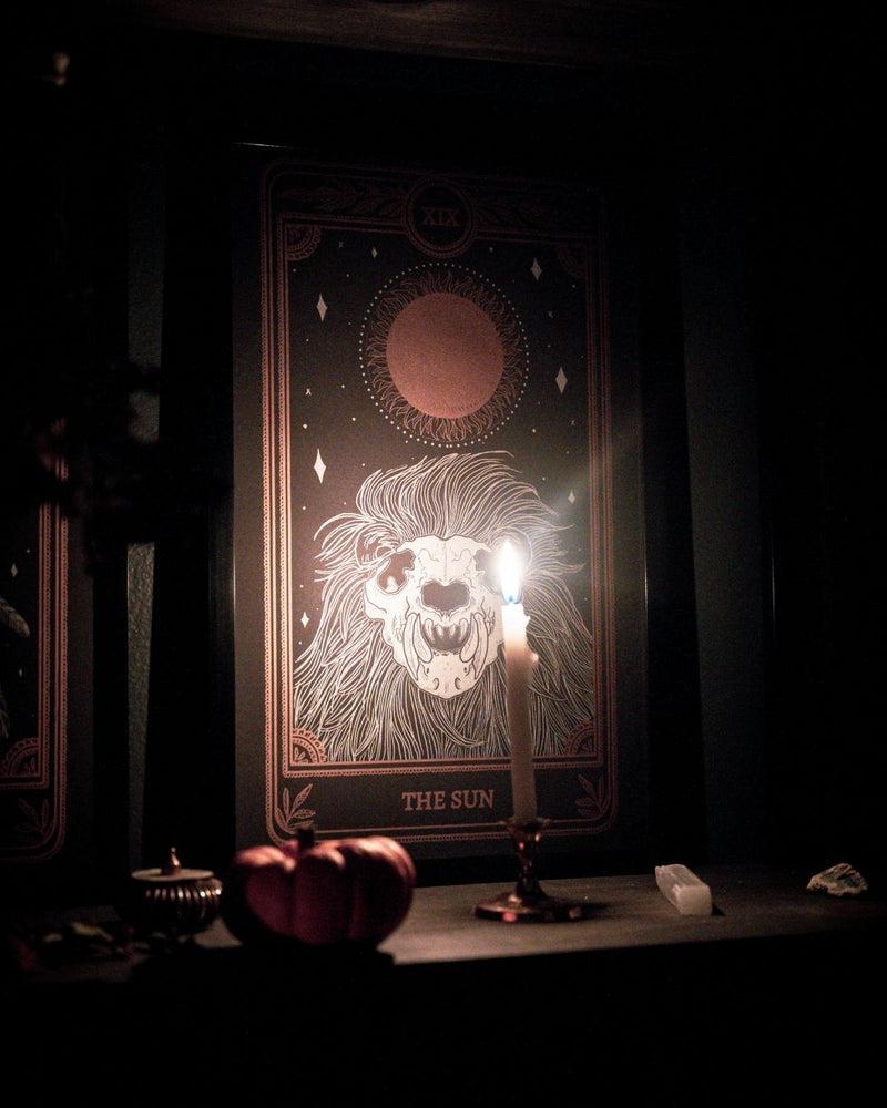 Tarot sun print with a black and gold ink and sun and skull. Candle light.