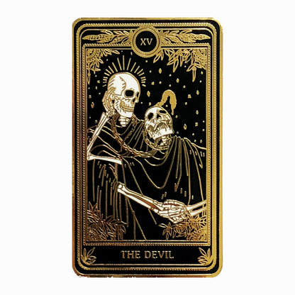 hard enamel pin, gold and black of the devil tarot card from the Marigold Tarot deck by Amrit Brar and 13th Press. Two skeletons and serpant